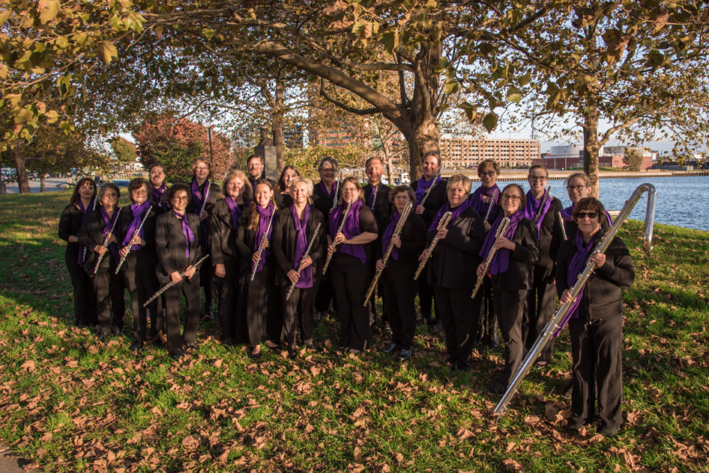 Baltimore Flute Choir holding flutes of various sizes with harbor coast in background
